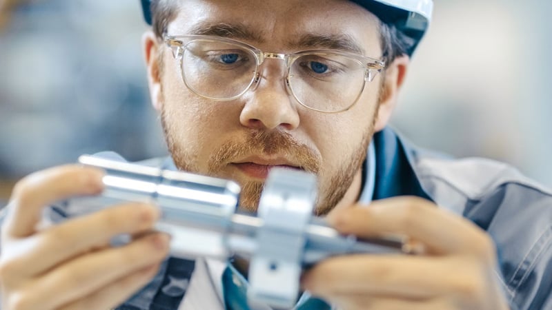 Close-up Shot of the Industrial Engineer Wearing Classes and Hard Hat Connects Two Components He Designed. Precision in Mechanical Engineering