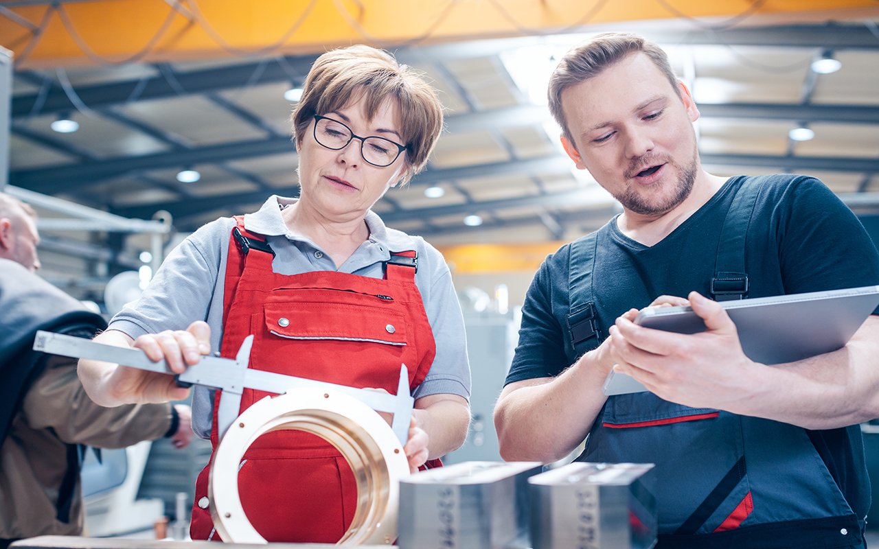 Workers measuring a metal workpiece